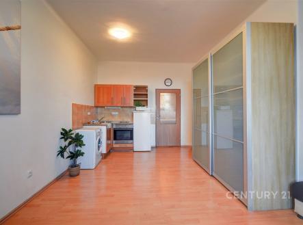 Kompaktní kuchyň s dřevěnou podlahou, světlými skříněmi a vestavěnými spotřebiči v moderním stylu. | Prodej bytu, garsoniéra, 26 m²