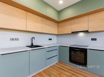 Moderní kuchyň s parketovou podlahou, vestavěnými skříněmi a elegantním designem. Kombinace dřeva a pastelových odstínů vytváří světlý prostor. | Prodej bytu, 3+kk, 54 m²