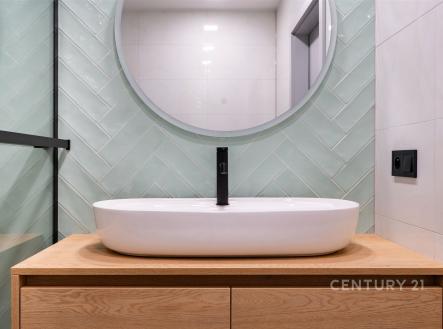Moderní koupelna s elegantním umyvadlem, dřevěným podstavcem a stylovými obklady zelené barvy, světlý a čistý designový interiér. | Prodej bytu, 3+kk, 54 m²