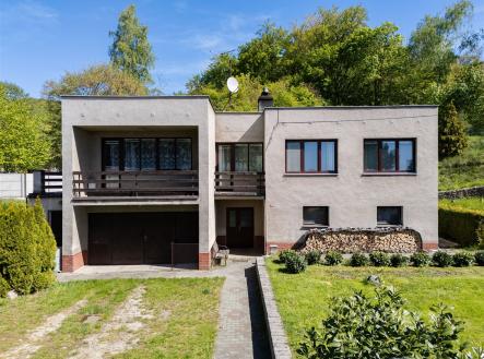Rodinný dům s plochou střechou, betonovou fasádou a prostorným balkonem, obklopený zelení, ideální pro rodinné bydlení na klidném místě. | Prodej - dům/vila, 198 m²
