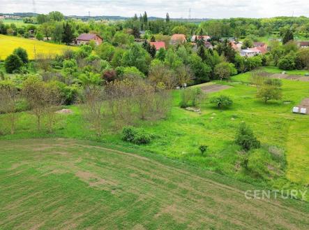 Rozlehlý stavební pozemek s travnatým porostem, obklopený zelení a blízkostí rodinných domů, ideální pro klidnou rezidenční výstavbu. | Prodej - pozemek pro komerční výstavbu, 1 463 m²