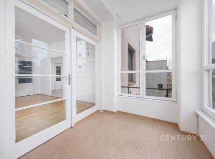 Světlá veranda s velkými okny, parketovou podlahou a moderním designem, nabízející výhled do klidného okolí. | Prodej bytu, 3+1, 141 m²