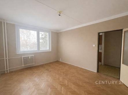 Světlý obývací pokoj s parketovou podlahou, velkými okny a neutrálními stěnami, ideální pro moderní bydlení. | Prodej bytu, 1+1, 32 m²