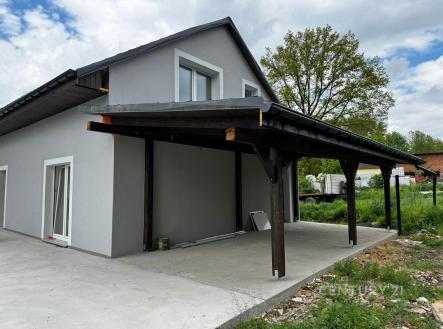 Samostatně stojící rodinný dům s moderní šedou fasádou a dřevěným přístřeškem. Vyniká klidnou lokalitou a prostorným okolním pozemkem. | Prodej - dům/vila, 190 m²