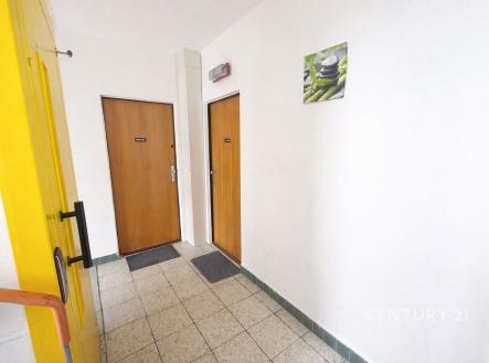 Společná chodba s dlažbou, bílými stěnami a dřevěnými dveřmi, moderní design vhodný pro bytový dům. | Prodej bytu, 2+1, 57 m²