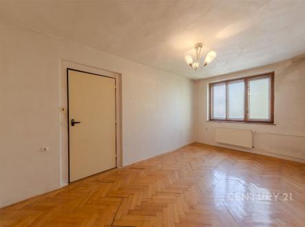 Světlý obývací pokoj s parketovou podlahou a velkými okny, moderní osvětlení a zdi připravené k renovaci. | Prodej - dům/vila, 160 m²