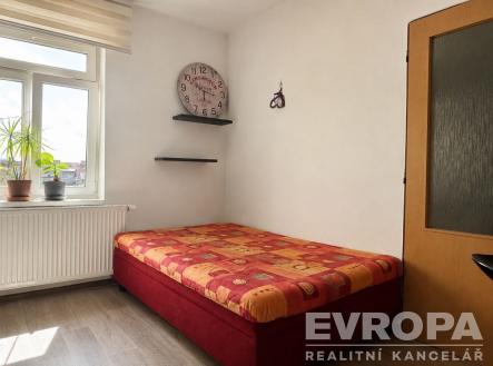 Světlá ložnice s dřevěnou podlahou, velkým oknem a moderním nábytkem, minimalistický design a útulná atmosféra. | Pronájem bytu, 1+kk, 25 m²