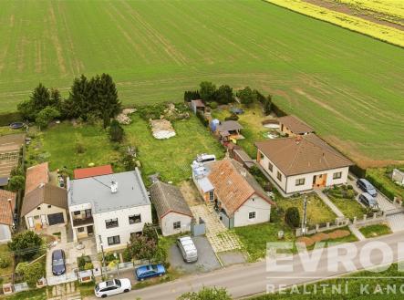 Pohled na klidnou venkovskou lokalitu s rodinnými domy, zahradami a okolními poli, nabízející soukromí a přírodu. | Prodej - dům/vila, 85 m²