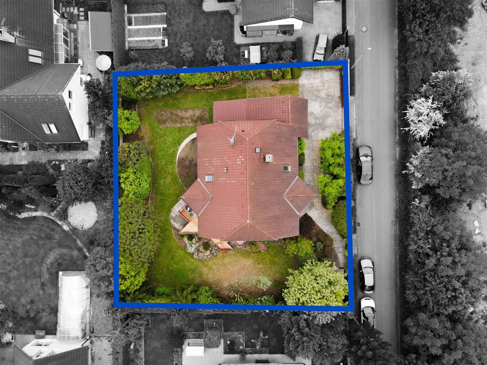 Letecký pohled na rodinný dům s červenou střechou obklopený zahradou, terasa a příjezdová cesta, klidná lokalita, ideální pro rodiny