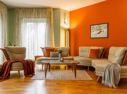 Světlý obývací pokoj s parketovou podlahou, moderní sedací soupravou a velkými okny. Teplé tóny stěn a doplňky vytvářejí útulnou atmosféru. | Prodej - dům/vila, 203 m²