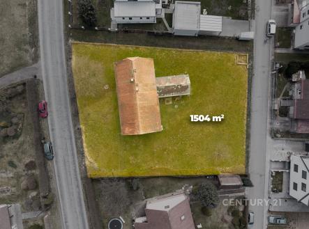 Letecký pohled na pozemek se starším domem s červenou střechou, rozloha 1504 m², klidná lokalita, ideální pro novou výstavbu nebo rekonstrukci. | Prodej - dům/vila, 95 m²