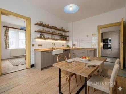 Kuchyně s dřevěnou podlahou, moderními vestavěnými spotřebiči a otevřenými policemi, které poskytují světlý a útulný prostor pro bydlení | Prodej - dům/vila, 95 m²