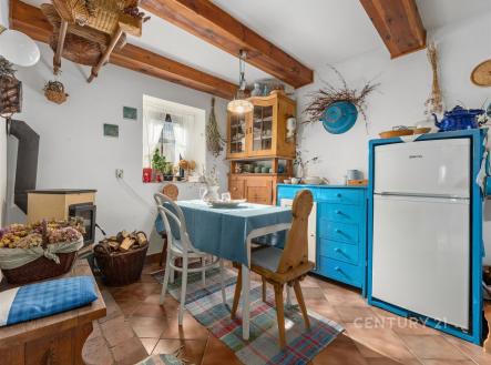 Rustikální kuchyň s dřevěnými trámy, dlažba, modrá a dřevěná kuchyňská linka, kamna na dřevo, útulný venkovský styl. | Prodej - dům/vila, 150 m²