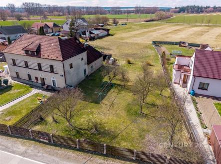 Prázdná zahrada s travnatým povrchem u rodinného domu, oplocená dřevěným plotem, ideální pro úpravu dle vlastních představ. | Prodej - pozemek pro bydlení, 1 825 m²