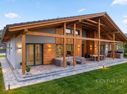 Prostorná terasa s dlažbou, dřevěné obložení, moderní design, velká okna propojující interiér s exteriérem, ideální pro relaxaci venku. | Prodej - dům/vila, 225 m²