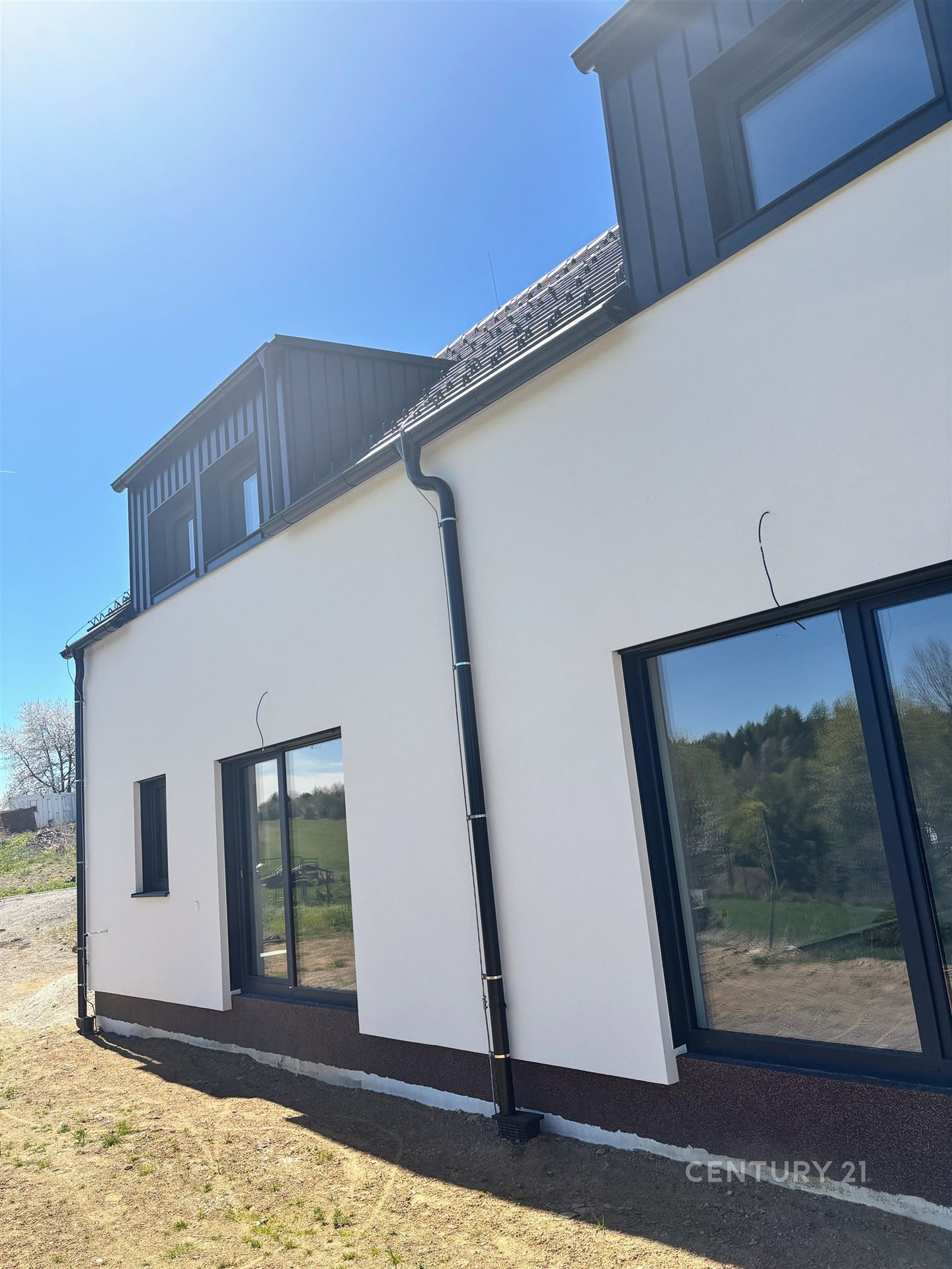 Moderní fasáda domu, velká okna, výhled na přírodu, kvalitní izolace, energeticky úsporný design, kombinace dřeva a omítky