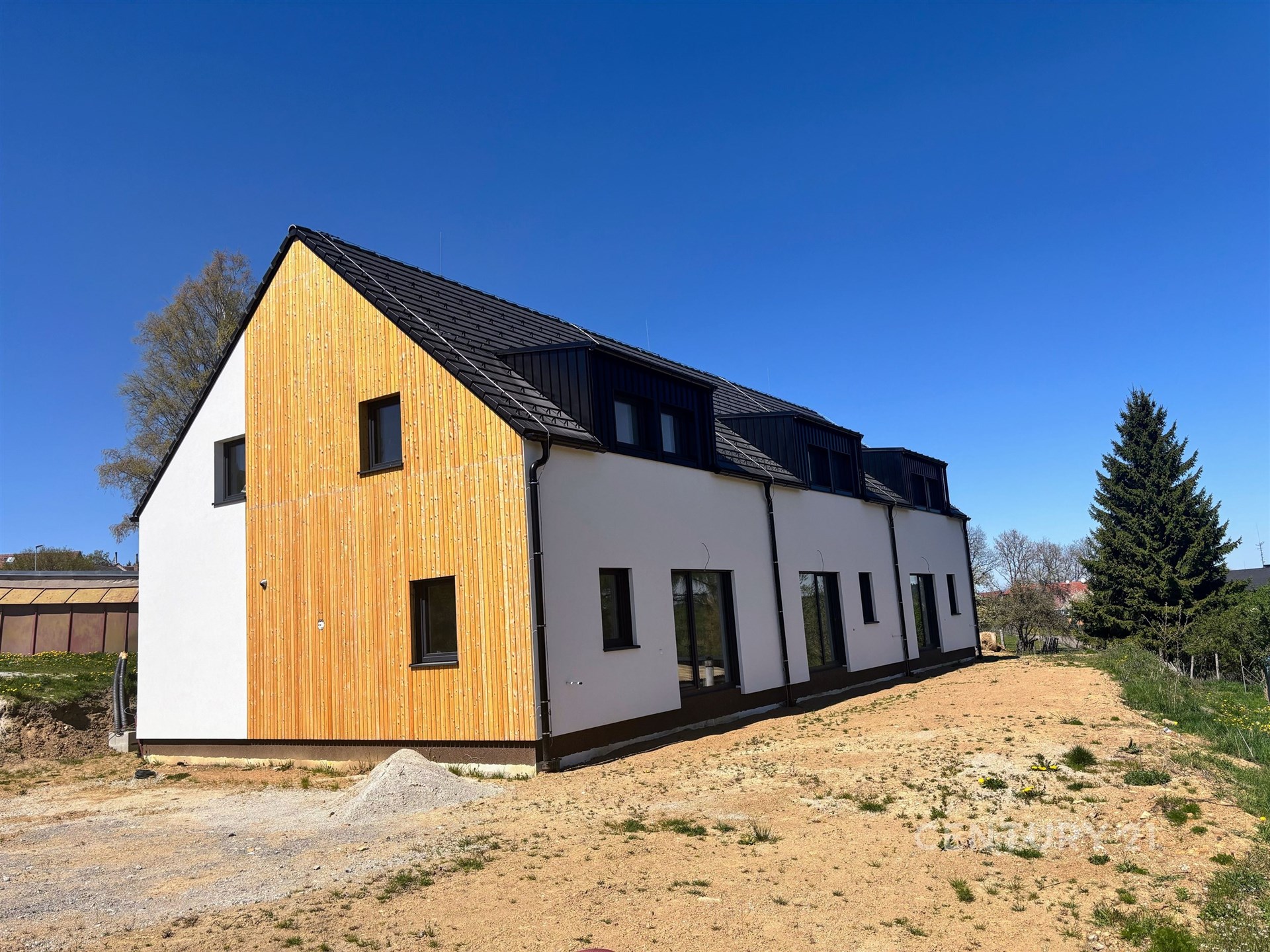Novostavba rodinného domu s moderní fasádou, kombinace dřeva a bílého omítky, velká okna, klidná lokalita, energeticky úsporná stavba