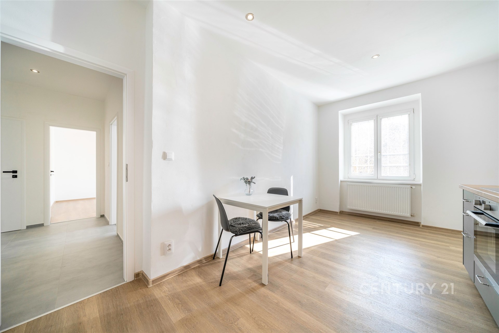 Světlá jídelna s parketovou podlahou, velkými okny a moderním vybavením, nabízí útulný a rekonstruovaný prostor pro stolování.