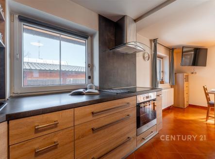 Moderní kuchyň s dřevěnou kuchyňskou linkou, vestavěnými spotřebiči a dlažbou, velká okna zajišťují světlou a přívětivou atmosféru. | Pronájem - dům/vila, 120 m²