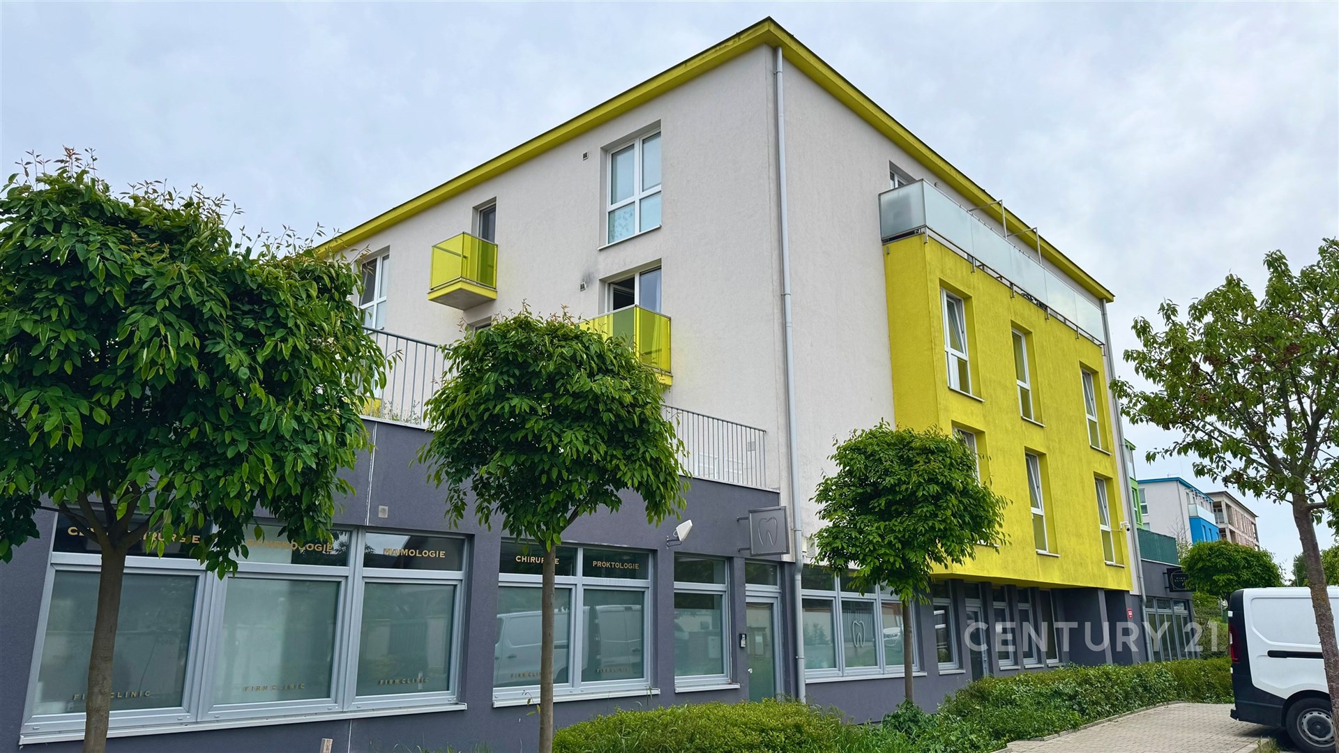 Moderní bytový dům s barevnou fasádou, plastovými okny a zelenými balkony, vhodný pro rodinné bydlení ve městě.