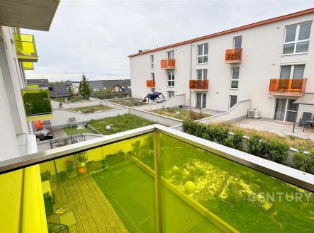 Balkon s moderním zábradlím, žluté sklo, výhled na udržovaný dvůr, novostavba bytového domu, klidná lokalita. | Pronájem bytu, 2+kk, 58 m²