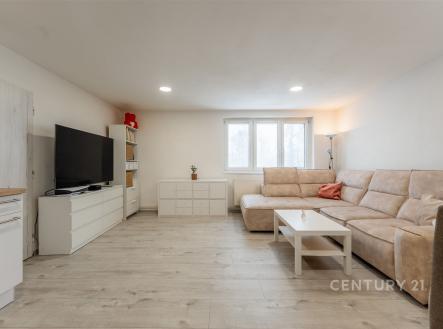 Světlý obývací pokoj s laminátovou podlahou, velká okna pro přirozené světlo, elegantní vestavěná skříň, moderní minimalistický design. | Prodej bytu, 4+kk, 74 m²