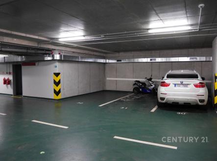 Podzemní parkovací garáž s moderním osvětlením, betonovými stěnami a parkovacími místy, vhodná pro bezpečné a kryté parkování. | Pronájem - malý objekt/garáž