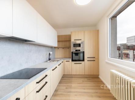 Moderní kuchyň s parketovou podlahou, vestavěnými spotřebiči a velkým oknem. Světlý a elegantní design nabízí praktické úložné prostory. | Prodej bytu, 3+1, 72 m²