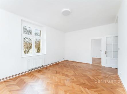 Světlý obývací pokoj s parketovou podlahou, velká okna a bílými stěnami, moderní styl a prostorný interiér vhodný pro rodinné bydlení. | Prodej bytu, 3+1, 92 m²