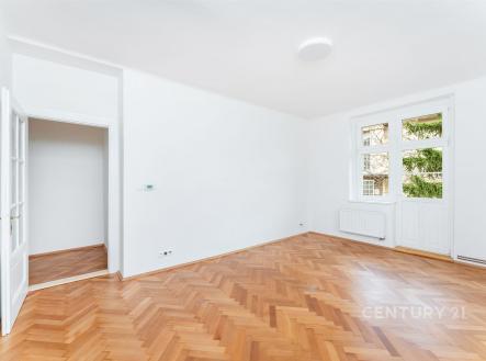 Světlý obývací pokoj s parketovou podlahou, bílými stěnami a velkými okny poskytujícími přirozené světlo, moderní interiér. | Prodej bytu, 3+1, 92 m²