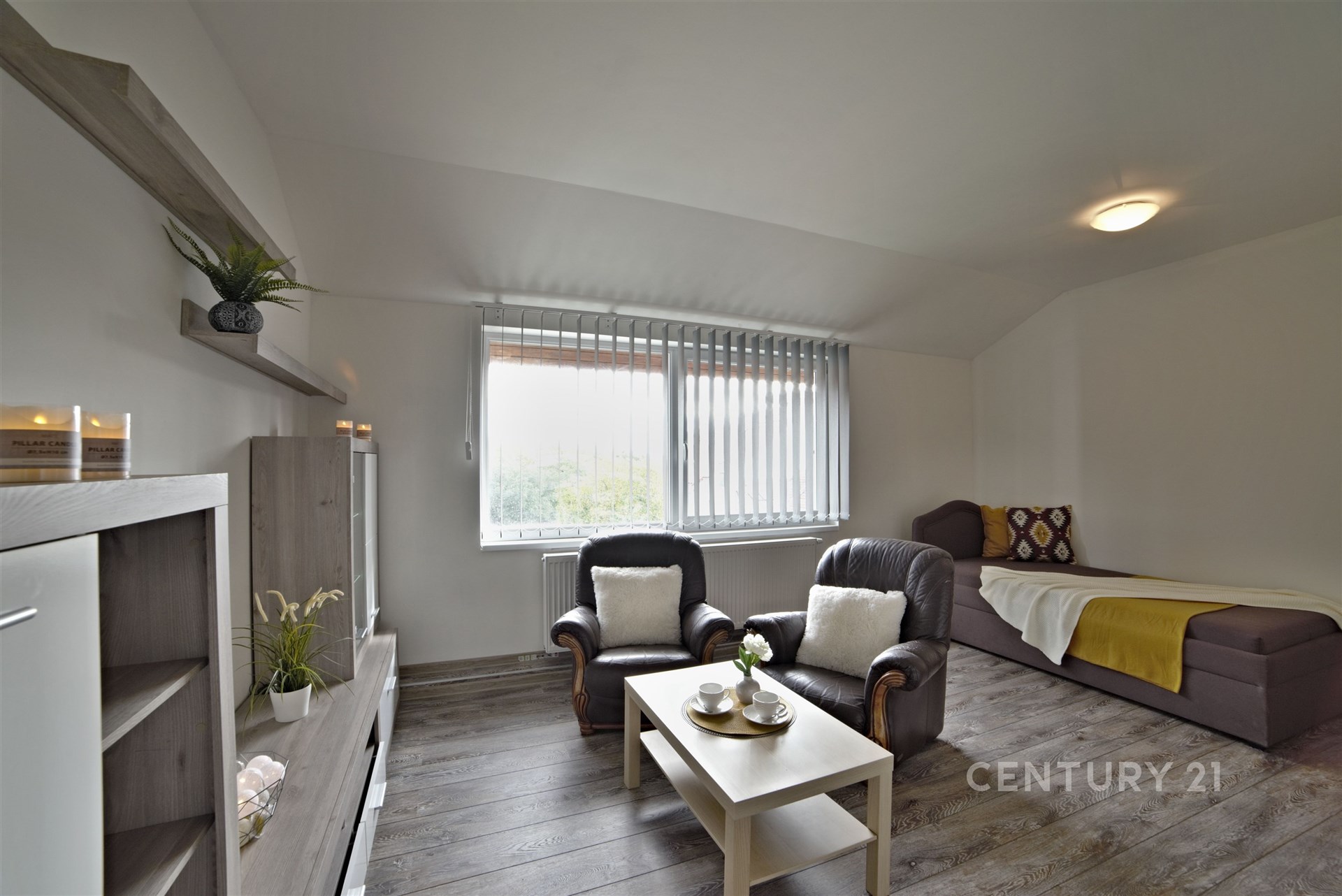 Světle zařízený obývací pokoj s parketovou podlahou, velkými okny a moderním nábytkem, nabízí útulný a světlý prostor k relaxaci.