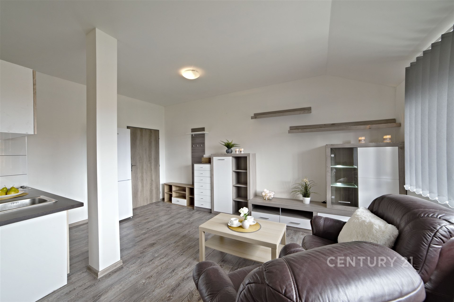 Světlý obývací pokoj s moderními prvky, plovoucí podlahou a velkými okny, nabízí komfortní prostor v rekonstruovaném bytě.