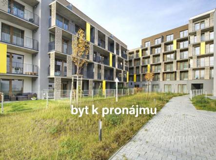 Moderní bytový komplex s balkonem, velká okna a upravený travnatý prostor. Stavba je moderní s pestrobarevnými fasádami. | Pronájem bytu, 2+kk, 47 m²