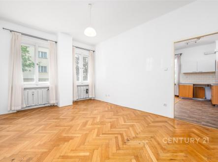 Světlý obývací pokoj s parketovou podlahou a velkými okny přechází do moderní kuchyně. | Prodej bytu, 2+kk, 49 m²