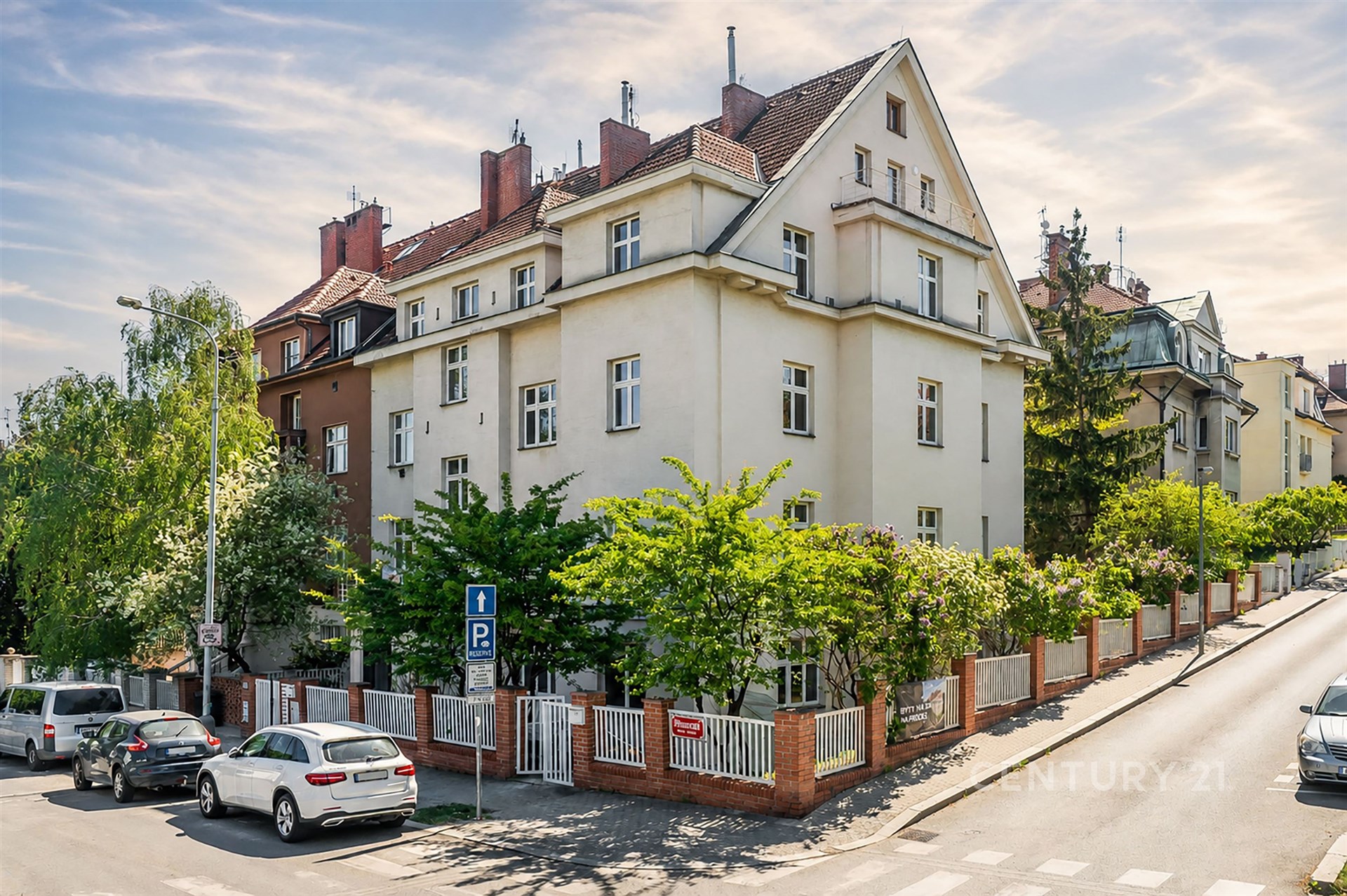 Rohový bytový dům ve městě, cihlová fasáda, velká okna, stylová zahrada, v klidné lokalitě.