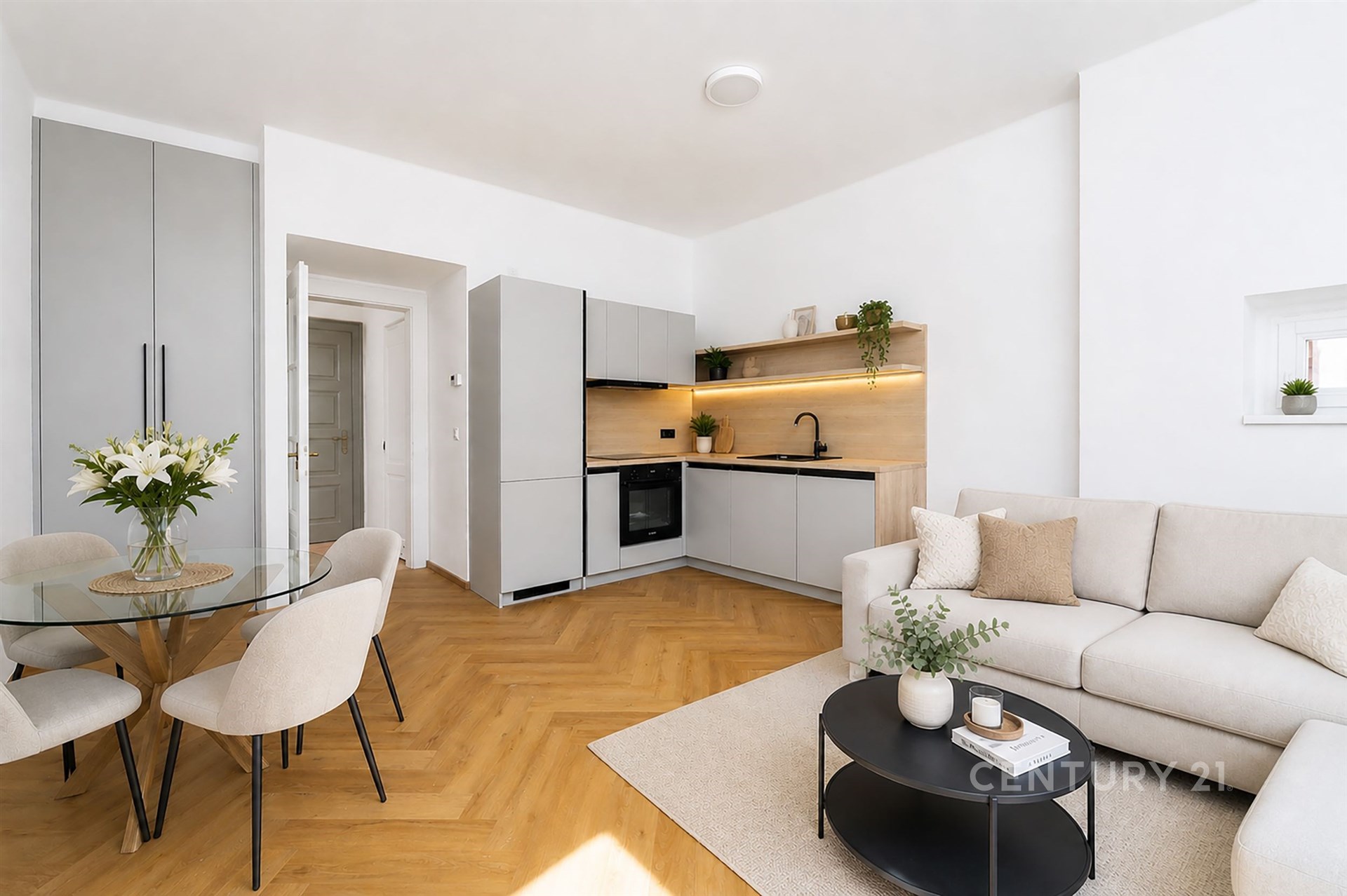 Světlý obývací pokoj s moderní kuchyní, parketová podlaha, velká okna, elegantní nábytek, světlý design, útulná atmosféra.