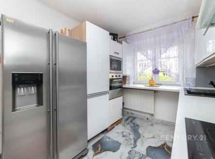 Moderní kuchyň s mramorovou dlažbou, vestavěnými spotřebiči a velkými okny, poskytujícími dostatek světla. | Prodej bytu, 3+1, 98 m²