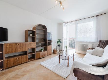 Světlý obývací pokoj s parketovou podlahou, velká okna a moderní nábytek, poskytuje příjemné posezení a propojení s balkonem. | Prodej bytu, 2+1, 47 m²