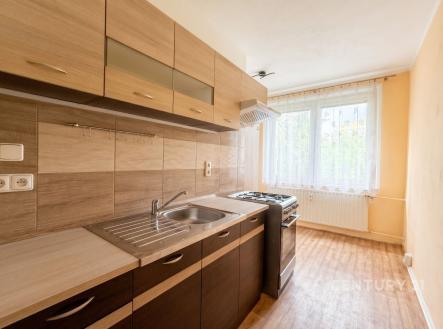 Kompaktní kuchyň s dřevěnou skříní, moderním vybavením a parketovou podlahou, velké okno přináší přirozené světlo. | Pronájem bytu, 1+1, 38 m²