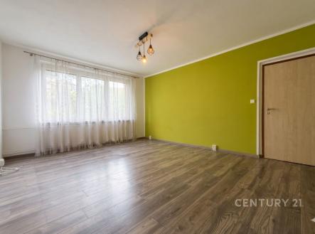 Světlý obývací pokoj s parketovou podlahou, velká okna a moderní osvětlení, zvýrazněná stěna v zelené barvě vytváří stylový interiér. | Pronájem bytu, 1+1, 38 m²