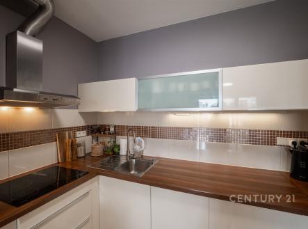 Moderní kuchyň s dřevěnou pracovní deskou, vestavěnými spotřebiči a keramickým obkladem, elegantní a funkční prostor. | Pronájem bytu, 2+kk, 60 m²