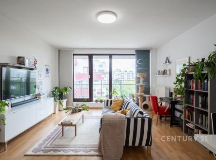 Světlý obývací pokoj s parketovou podlahou, velkými okny a moderním nábytkem, které vytvářejí útulnou atmosféru. | Pronájem bytu, 2+kk, 60 m²