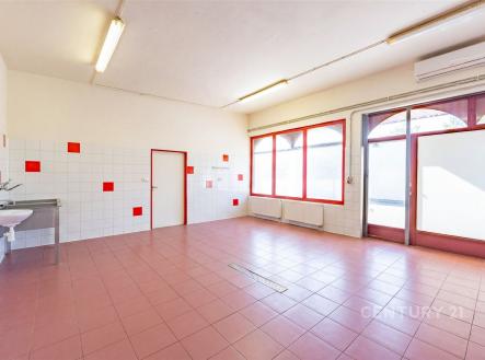 Světlá víceúčelová místnost s dlažbou, velkými okny a moderním osvětlením, ideální pro komerční využití nebo rekonstrukci. | Prodej - výrobní prostor, 163 m²