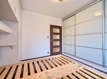 Ložnice s vestavěnými skříněmi, parketovou podlahou a moderními posuvnými dveřmi, ideální pro světlý a funkční interiér. | Pronájem bytu, 3+1, 74 m²