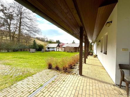 Prostorná terasa s dlážděnou podlahou nabízí výhled na rozlehlou zahradu, v pozadí se nachází přístavky a obklopuje ji přírodní zeleň | Prodej - chata/rekreační objekt, 273 m²