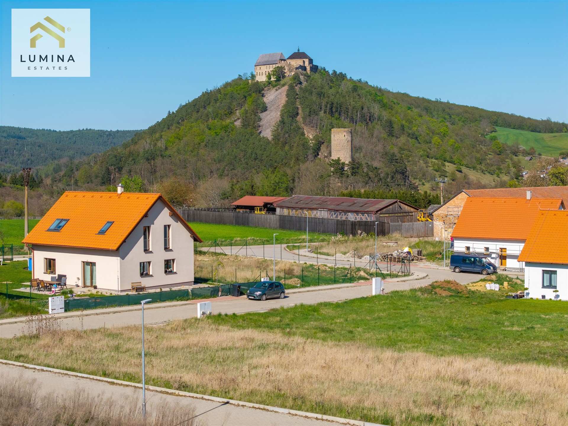 Novostavba rodinného domu s oranžovou střechou, nabízející klidné bydlení. Prostorná zahrada ideální pro rodinu, skvělý výhled na krajinu.
