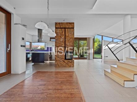 Prostorný obývací pokoj s parketovou podlahou a krbovými kamny, velká okna zajišťují světlý interiér, moderní architektonické prvky. | Prodej - dům/vila, 329 m²