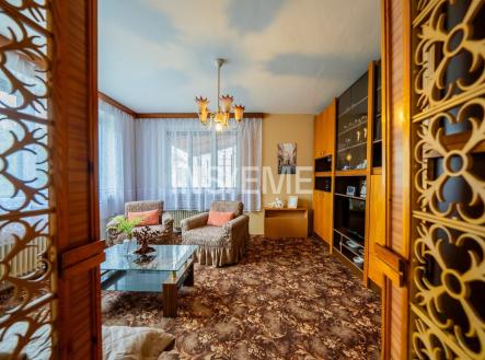 Světlý obývací pokoj se starožitným nábytkem, velká okna, dřevěné detaily a koberec s vzorem, zachovalý retro styl. | Prodej - dům/vila, 152 m²