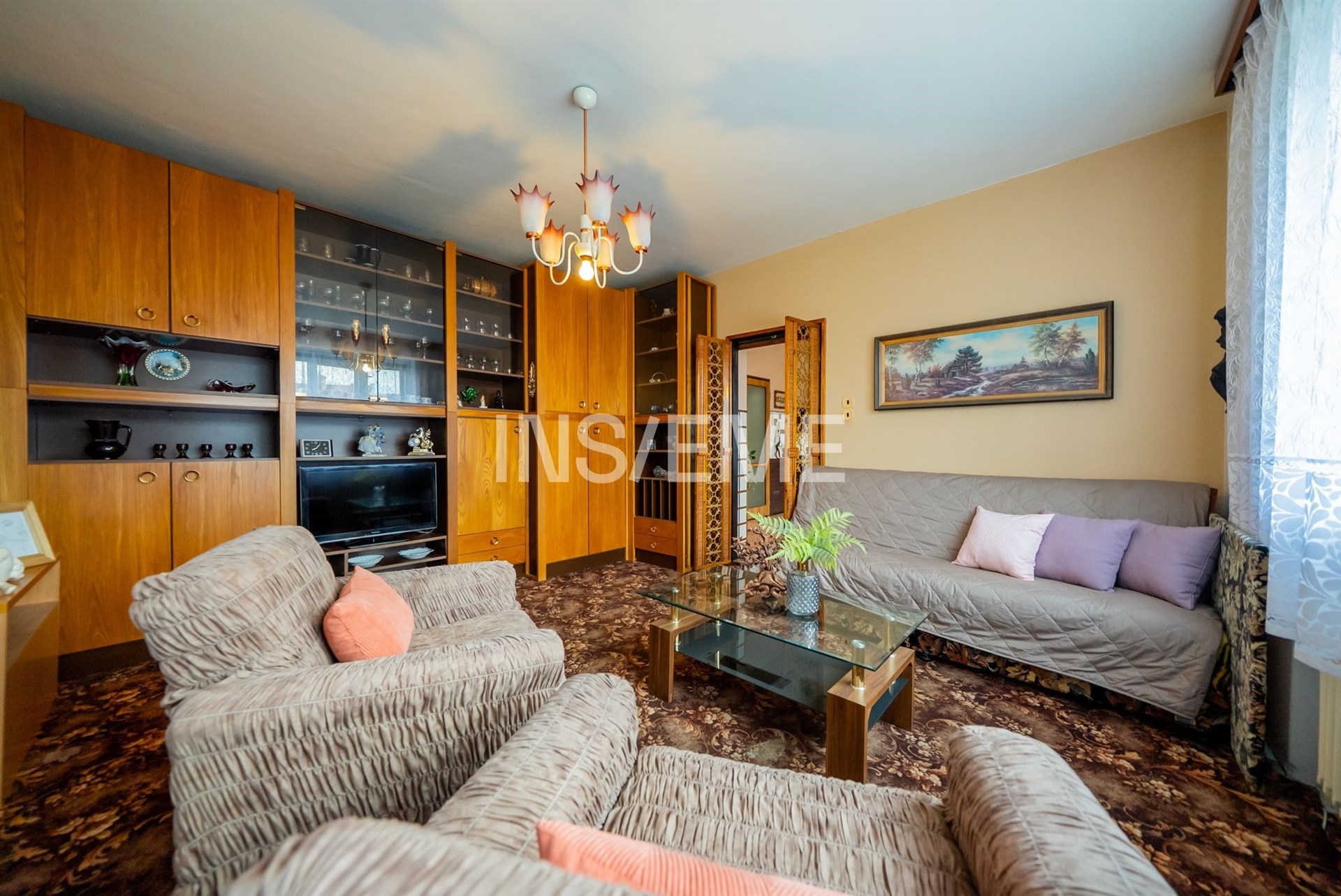 Obývací pokoj s vestavěnými skříněmi, dřevěným nábytkem a kobercovou podlahou, nabízí prostorné a útulné prostředí.