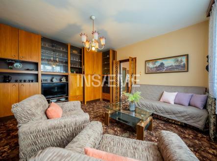 Obývací pokoj s vestavěnými skříněmi, dřevěným nábytkem a kobercovou podlahou, nabízí prostorné a útulné prostředí. | Prodej - dům/vila, 152 m²